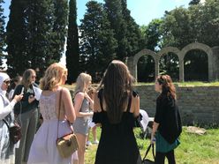 students listen to instructor in front of ruins